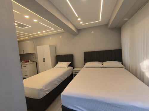 two beds in a small room with white sheets at Vizyon Konak in Burhaniye