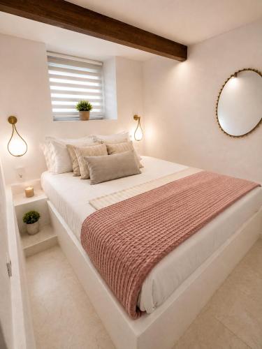 a white bedroom with a large bed with a mirror at Ktima Voulme in Kavála