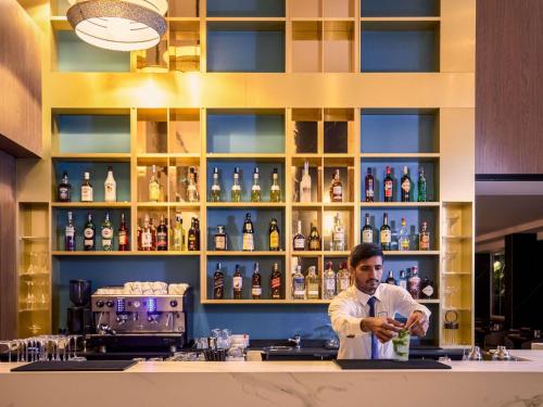 a man standing behind a bar making a drink at Novotel Malta Sliema in Il-Gżira