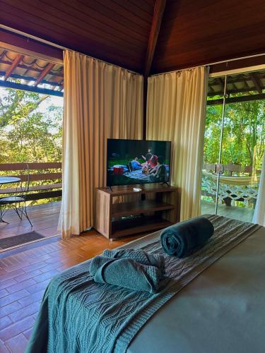 a bedroom with a flat screen tv and a bed at Pousada Vila de Charme in Lençóis