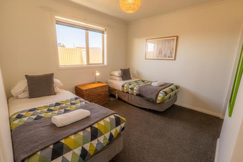 a room with two beds and a window at Relax on Rata, Cottage 2 in Twizel