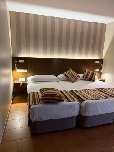 a bedroom with two beds and a headboard at Hostal Los Coronales in Madrid