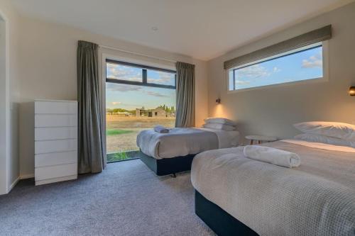 a bedroom with two beds and a large window at 31 on Boundary in Twizel