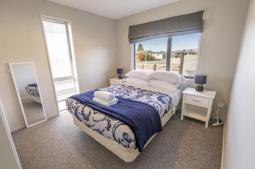a bedroom with a bed and a large window at Irishman Drive Escape in Twizel