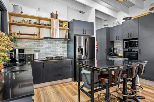 a kitchen with gray cabinets and a black island with bar stools at Creekside Cottage, pet friendly w pool in Perwillowen