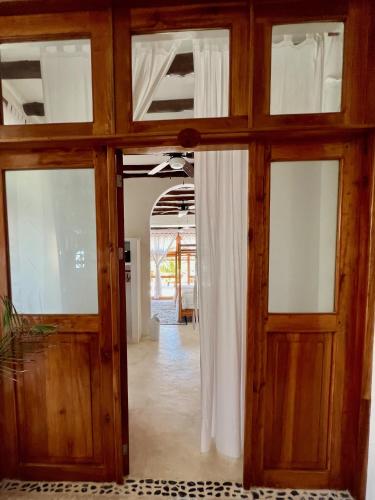 a room with wooden doors and curtains in a room at Palapas del Sol in Holbox Island