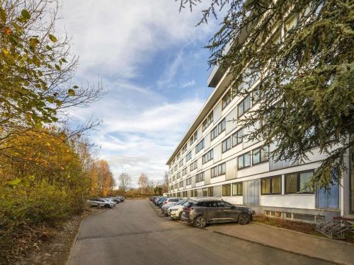 a building with cars parked in a parking lot at Novotel Brussels Airport in Diegem