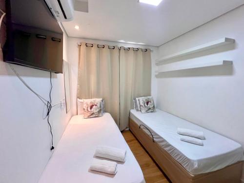 a small room with two beds and a tv at Apartamento 2 quartos com Vista in Bauru