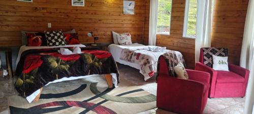 a bedroom with two beds and a pink chair at Miriam'S Quetzals lodge in San Gerardo de Dota