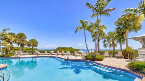 a swimming pool with palm trees and chairs at Pristine Islamorada Pool Home with Ocean View and Dockage in Islamorada