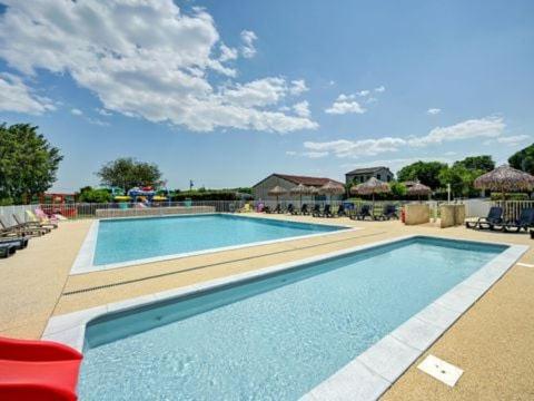 a large swimming pool in a resort with a red chair at Camping Olé camp in Balazuc