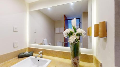 a bathroom with a sink with a vase of flowers at Park Royal Mazatlán in Mazatlán