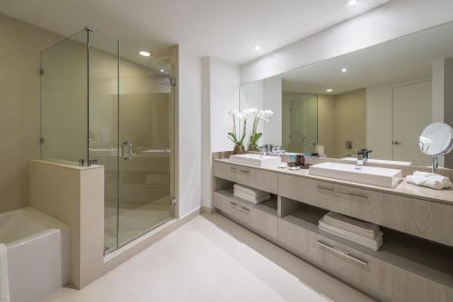 Un baño con dos lavabos, una ducha y un espejo. en Lyfe Resort & Residences, en Hollywood