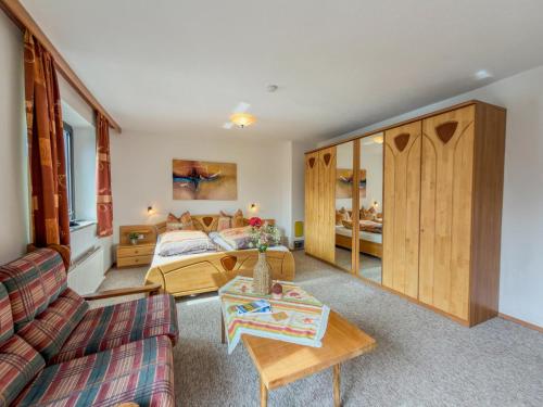 a bedroom with a bed and a couch and a table at Landhaus Herz der Tauern in Mallnitz