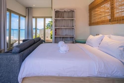 a bedroom with a large white bed and a couch at Absolute Oceanfront Tara Villa Beachfront 4 Bed in Ban Saiyuan (1)