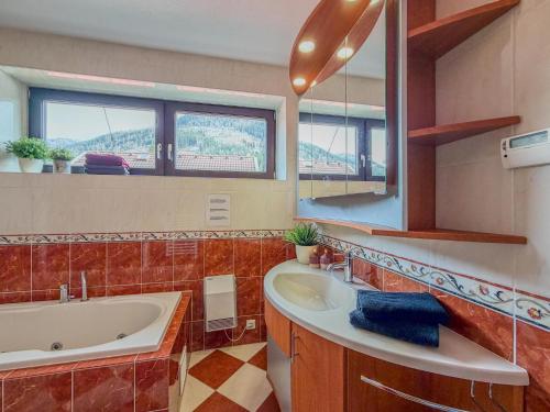 a bathroom with a sink and a tub and a mirror at Landhaus Herz der Tauern in Mallnitz