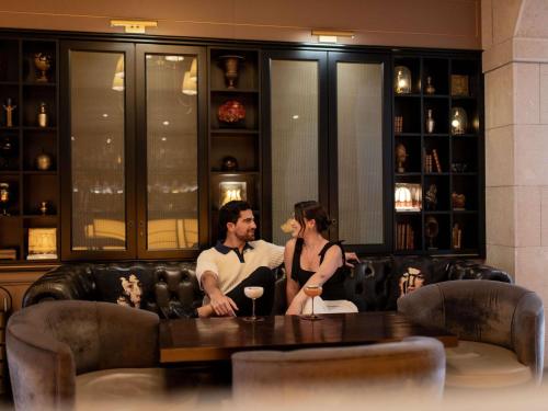 Ein Mann und eine Frau sitzen auf einem Sofa in der Unterkunft Hotel Rotary Geneva - MGallery in Genf