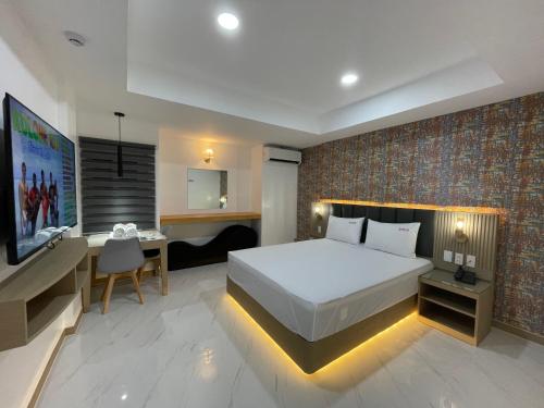 a bedroom with a bed and a desk and a television at Maganda Hotel - San Fernando in San Fernando