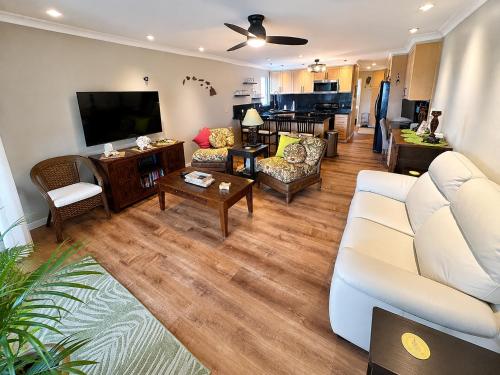 a living room with a white couch and a tv at Wavecrest - 4BR Condos - Sleeps 12 in Kaunakakai