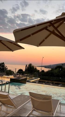 a swimming pool with two chairs and an umbrella at Hotel Oasis in Sarandë