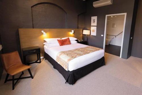 a bedroom with a large bed and a chair at Harbour Rocks by Ode Hotels in Sydney
