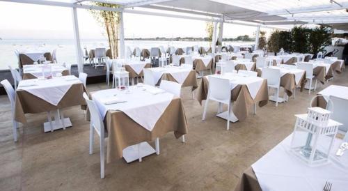 a room with white tables and chairs and the ocean at Casa Roby 120 mt Beach in Fontane Bianche