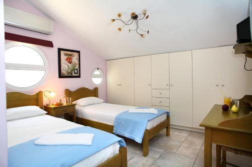 a bedroom with two beds and a desk and a window at Liogerma Villas in Agios Nikitas