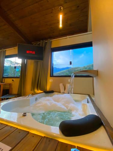 a jacuzzi tub in a room with two windows at Casa no Centro de São Francisco Xavier in São José dos Campos