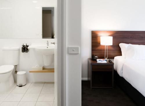 a bedroom with a bed and a bathroom with a sink at Mantra Hobart Airport in Hobart