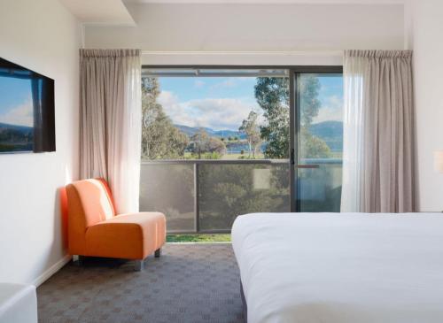 a hotel room with a bed and a large window at Mantra Hobart Airport in Hobart