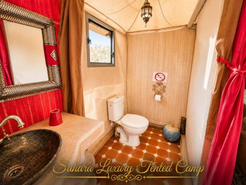 a bathroom with a toilet and a sink and a mirror at Sahara Luxury Tented Camp in Merzouga