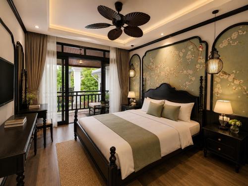 a bedroom with a bed and a desk and a balcony at Luang Prabang Indochine Heritage Hotel in Luang Prabang