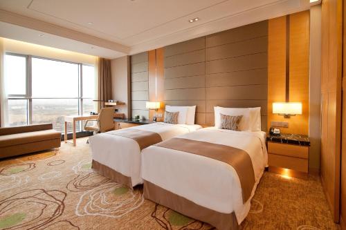 two beds in a hotel room with a large window at Crowne Plaza Shanghai Anting-20 Minutes drive to National Exhibition and Convention Center & 15 Minutes drive to F1 in Jiading