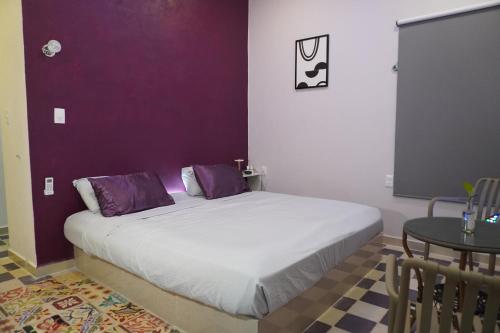 a bedroom with a bed with purple walls and a table at Pequeño Refugio in Ticul