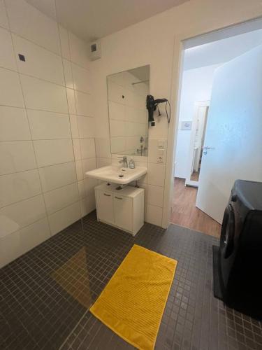 a bathroom with a sink and a mirror and a yellow rug at Imperial Baths Boutique Studio in Trier