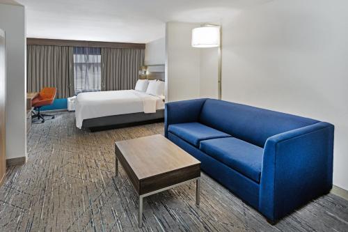 a hotel room with a blue couch and a bed at Holiday Inn Express & Suites - Laredo-Event Center Area by IHG in Laredo