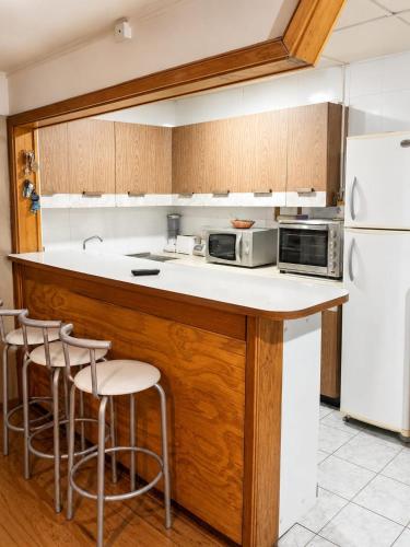 a kitchen with a counter with stools and a microwave at Hostal y piezas individuales in Coihaique