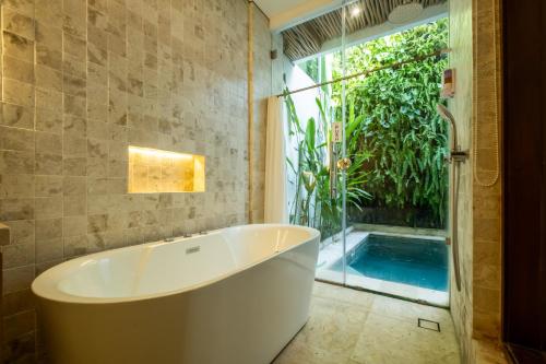 a bathroom with a tub and a swimming pool at Bali Residence Villa in Uluwatu