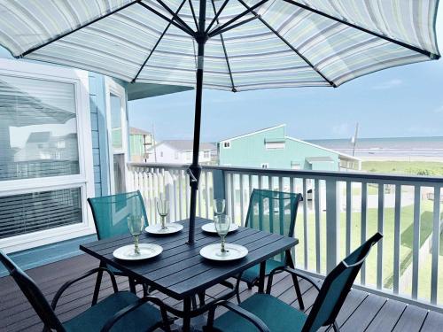 a black table with chairs and an umbrella on a balcony at Sandy Beach Retreat and Gulf View in Galveston