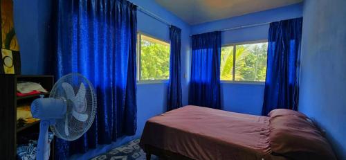 a bedroom with blue walls and a bed with a fan at Casa de Descanso - Camelia in Monte Gordo