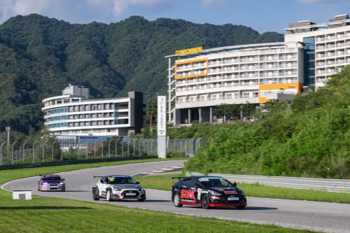 two cars racing on a race track with a building at Take Hotel & Resort Inje Speedium in Inje