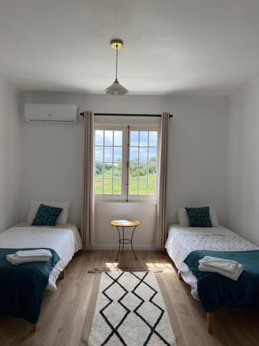 a room with two beds and a table and a window at Hydrangea House in Água de Pau