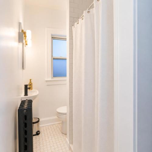 a bathroom with a toilet and a white shower curtain at High Falls Studio TV Kitchen Downtown Rochester in Rochester
