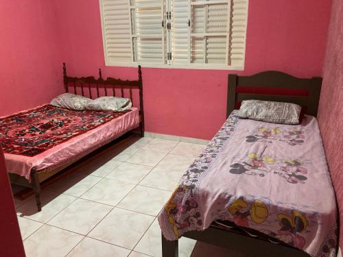 two beds in a room with pink walls at Casa de temporada Passos MG in Passos