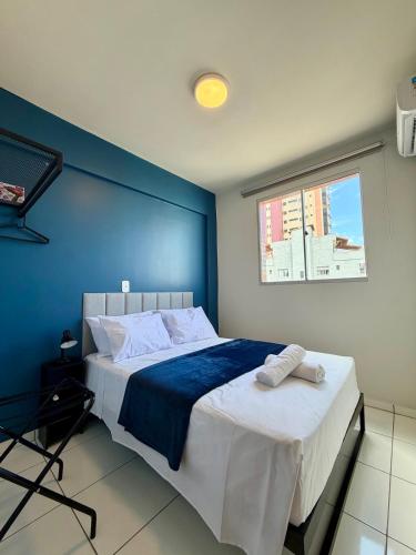 a bedroom with a large bed with a blue wall at Apto com 2 quartos e A/C no Centro in Montes Claros