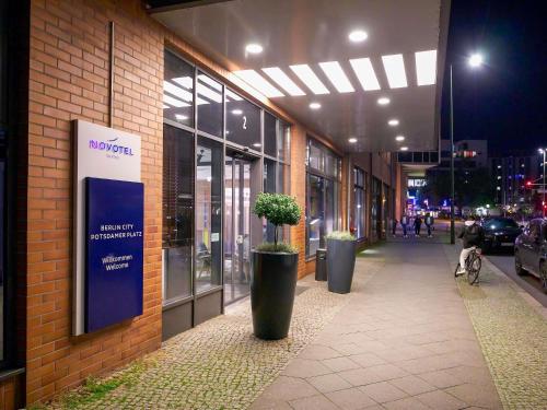 a sidewalk in front of a building with potted plants at Novotel Suites Berlin City Potsdamer Platz in Berlin