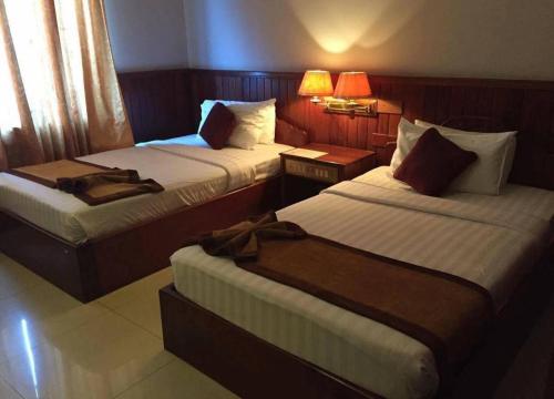 a hotel room with two beds and two lamps at Mongkol Angkor Residence in Phumĭ Trăm Néak