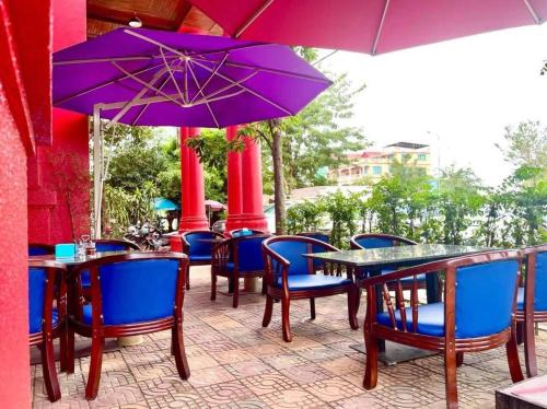 a patio with tables and chairs and purple umbrellas at Mongkol Angkor Residence in Phumĭ Trăm Néak