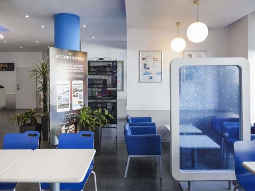 a waiting room with blue chairs and a large screen at Ibis Budget Málaga Centro in Málaga