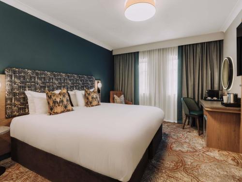 a hotel room with a large bed and a desk at Mercure Exeter Southgate Hotel in Exeter